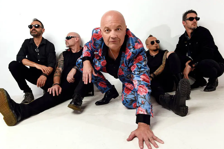 Australian rock band Chocolate Starfish posing together on a white background with frontman Adam Thompson in a floral suit.
